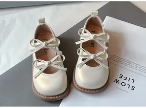 Detalle de zapatos Mary Jane para niña en color crema con doble lazo y suela blanda.