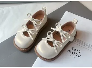 Detalle de los elegantes zapatos de princesa color crema para niñas con doble lazo