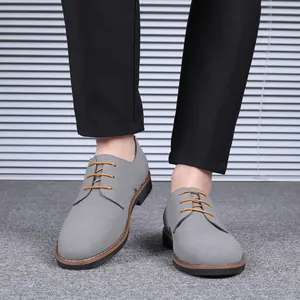 Gros plan de chaussures derby en daim gris pour hommes avec lacets orange et pantalon