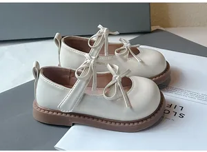 Primer plano de zapatos Mary Jane crema para niñas con elegantes lazos dobles y suela blanda.