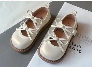 Vista detallada de elegantes zapatos Mary Jane crema para niñas con lazos dobles.