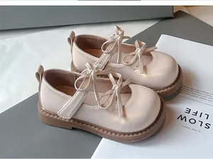 Primer plano de elegantes zapatos Mary Jane color crema para niña con doble lazo.