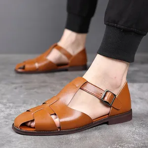 Detailweergave van bruine leren dichte herensandalen met zijgesp sluiting.
