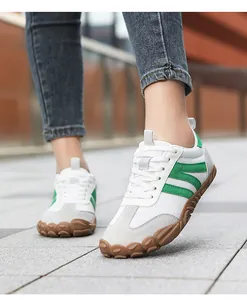 Close-up of white barefoot walking shoes with green stripes and rugged brown rubber sole