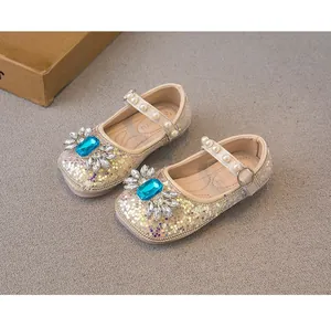 Close-up detail of champagne glitter princess shoes with blue gemstones and pearl strap decoration