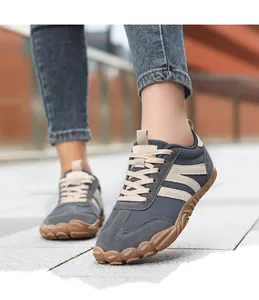 Detailed view of grey barefoot hiking shoes with wide toe box design on outdoor tile flooring