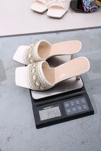 Detailed weight measurement of white Bohemian square toe high heel sandals on a scale