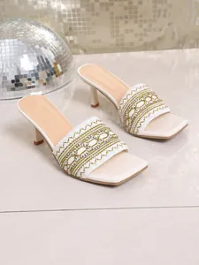 Macro view of white Bohemian high-heel sandals with intricately embroidered straps