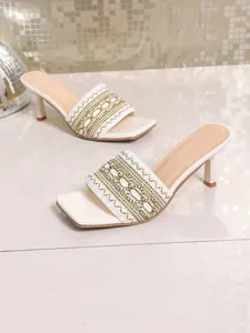 Detail of white bohemian heeled sandals with intricate embroidered strap design.