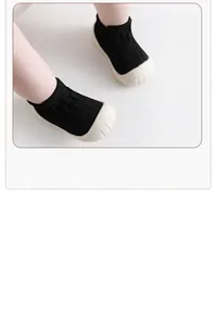 Close-up of baby floor shoes with black knit upper and soft white rubber sole