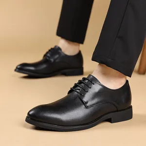 Detalle de zapatos de vestir formales con cordones en cuero negro para hombre en modelo