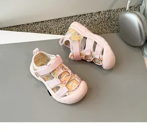 Primer plano de sandalias rosas para niños con punta cerrada, motivos geométricos y velcro.
