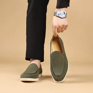 Man die legergroene suède loafers draagt en vasthoudt in een professionele studio