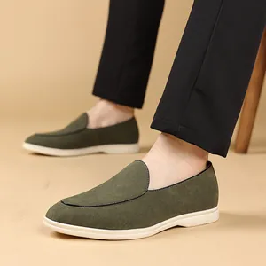 Detailweergave van olijfgroene suède loafers met witte zolen aan de voeten van een man.