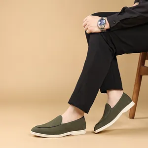 Gedetailleerd zicht op olijfgroene suède herenloafers met zachte witte zool op model.