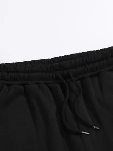 Détail de la taille élastique et du cordon de serrage d'un pantalon de sport noir.