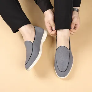 Detailopname van grijze herenloafers met suèdetextuur gedragen met zwarte casual broek