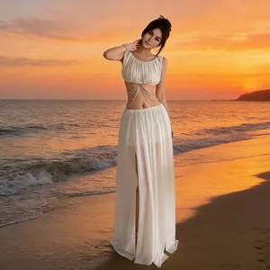 Elegant white mesh two-piece set with decorative chain detail shown on a sunset beach.