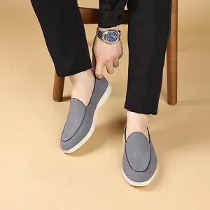 Close-up van grijze herenloafers met zachte witte zolen en getextureerde stof.