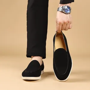 Close-up van zwarte suède herenloafers met flexibele witte zolen.