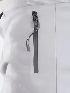Dettaglio ravvicinato della tasca con cerniera verticale nera su pantaloncini bianchi