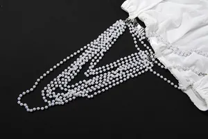 Close-up of white mesh skirt featuring elegant multi-strand faux pearl chain details