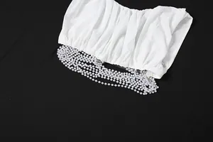 Detail of fashionable white pleated mesh top with multi-strand pearl chain accents