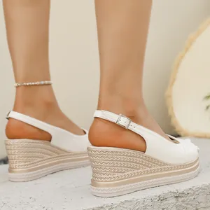 Dettaglio di eleganti sandali bianchi con zeppa, suola platform intrecciata e cinturino a fibbia.
