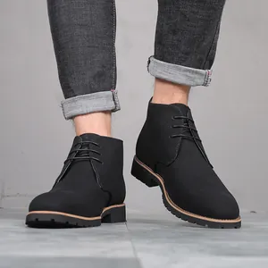Close-up of men's black suede lace-up desert boots on model legs in a studio setting