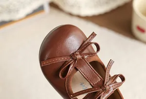 Close-up of brown girl's Mary Jane shoes with double bow detail and T-strap.
