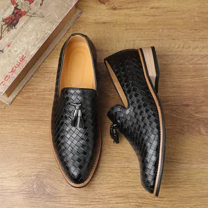 Close-up of black woven leather loafers with decorative tassels on wooden background