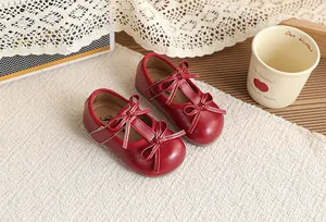 Close-up of vintage red girl's Mary Jane shoes with elegant bow decorations and velcro straps