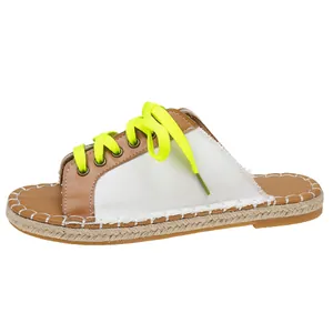 Detailaufnahme der Leinwandtextur und der neongelben Schnürsenkel einer flachen Damen-Espadrille