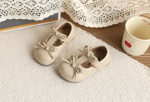 Detailed view of beige toddler girls' Mary Jane flat shoes with double bow decorations.