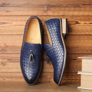 Macro detail of men's blue woven leather loafers with tassel accents on wooden background