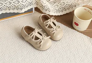 Close-up detail of beige British style girls Mary Jane shoes with elegant double bow design.