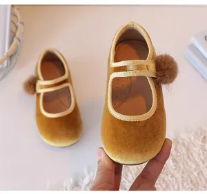 Detail van gele fluwelen Mary Jane schoenen voor meisjes met zachte pompon-versiering