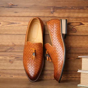 Detail view of brown woven texture men's loafers with tassel decor on wood background