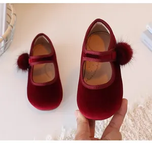 Detailopname van rode fluwelen Mary Jane meisjesschoenen met zachte pompoms