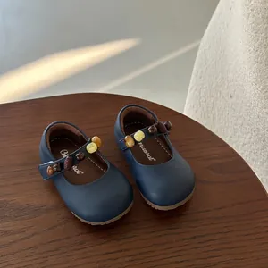 Detail van donkerblauwe Mary Jane kinderschoenen met gekleurde kralen op houten kruk