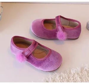 Gedetailleerde weergave van paarse fluwelen meisjesschoenen met pompon-decoratie