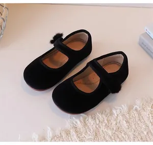 Detailweergave van zwarte fluwelen Mary Jane schoenen voor meisjes met zachte bontbal.
