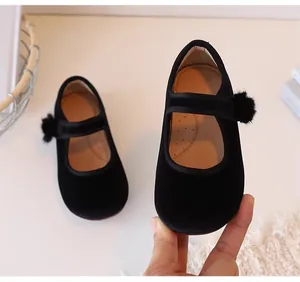 Close-up van zwarte fluwelen Mary Jane schoenen voor meisjes met een decoratieve bontbal