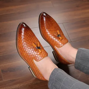 Close-up view of men's tan tassel loafers with intricate woven texture, worn on feet.