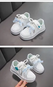 Détail de baskets blanches pour filles avec nœud en dentelle bleue et écussons mignons