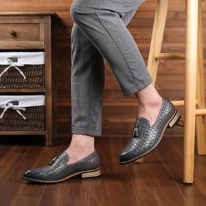 Macro detail view of men's gray woven leather loafers with decorative tassel accents.