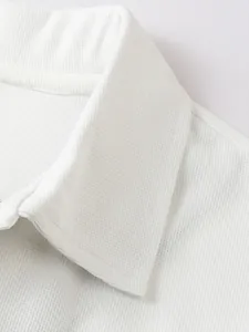 Gros plan détaillé d'un polo blanc en maille gaufrée montrant la texture du col.