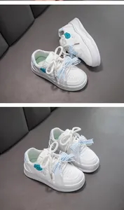 Détail de baskets blanches pour filles avec nœuds en dentelle vichy bleu et semelles