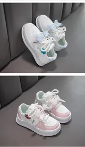 Gros plan sur des baskets blanches pour filles avec de jolis nœuds en dentelle rose et bleu