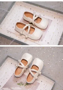 Detailed view of cream floral jacquard girl shoes with pearl straps and soft sole.